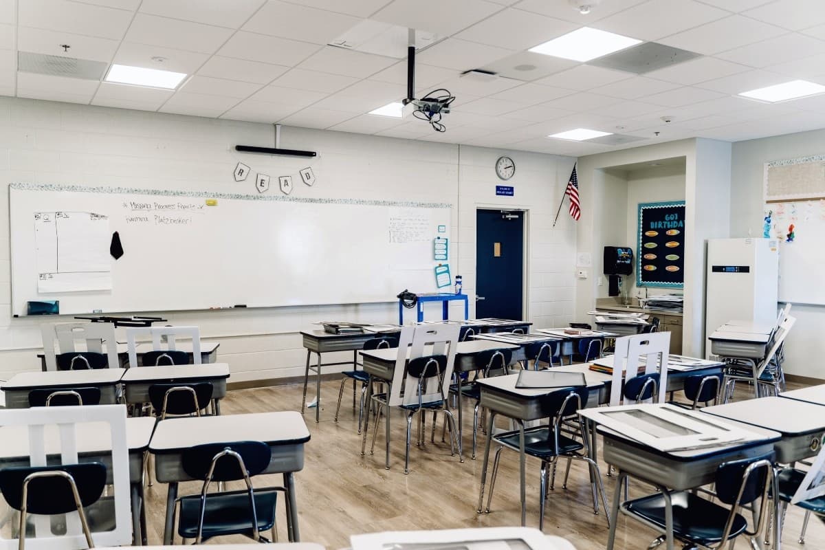 A tidy, empty K-12 classroom with student desks and a U.S. flag.